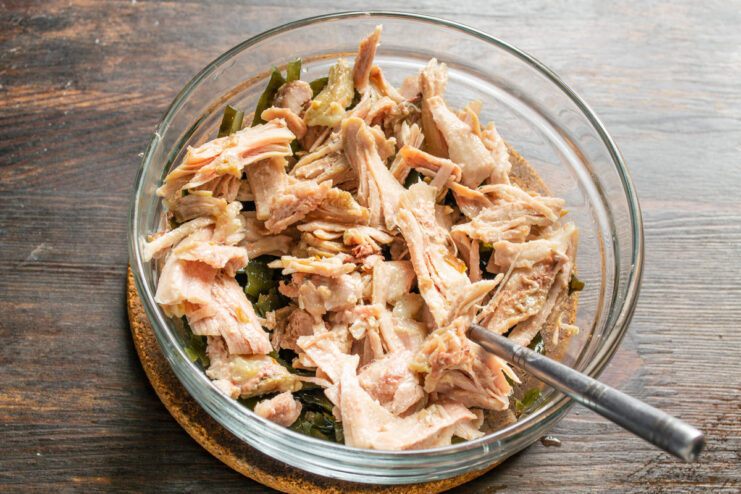 Step 2: Adding Cooked Chicken to the Salad Cooked chicken pieces being added to the bowl with kelp.