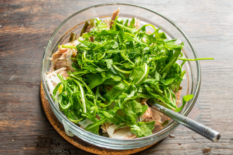 Step 4: Washing Fresh Arugula for the Salad A handful of fresh, green arugula leaves being washed under running water.