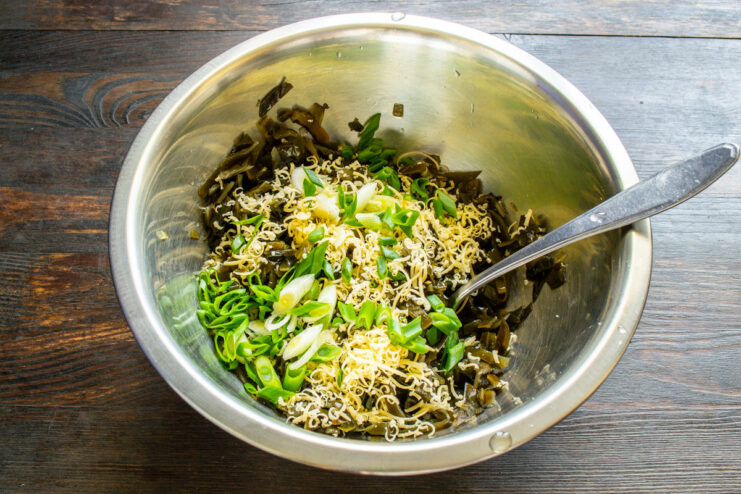 Adding fresh green onions to the salad Adding freshly chopped green onions to a bowl with other salad ingredients.