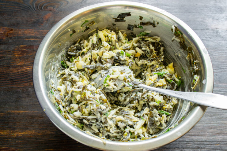Tossing the salad with the creamy dressing Mixing the seaweed salad with the creamy homemade dressing in a glass bowl.