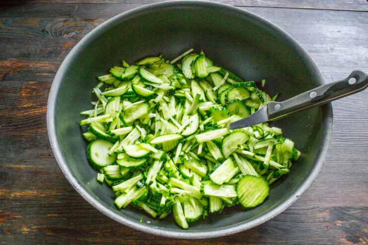 How to Perfectly Julienne Cucumbers for the Salad Fresh cucumbers being julienned into fine strips on a cutting board for a winter salad.