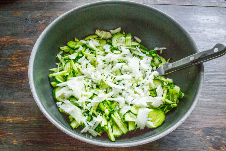 Dicing Onions for a Flavorful Salad Base A hand dicing a yellow onion into small cubes on a wooden board.