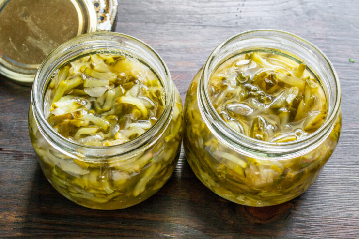 Properly Packing Jars for Long-Term Storage Packing the hot cucumber and garlic scape salad into sterilized glass jars for canning.