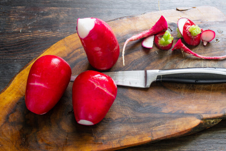 Preparing Radishes: Trimming and Washing for the Salad Freshly washed red radishes with their tops and tails trimmed, ready for slicing.