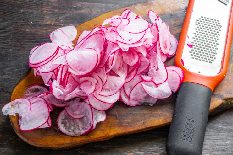 Slicing Radishes Thinly for a Delicate Texture Slicing red radishes into thin, almost transparent rounds on a cutting board.