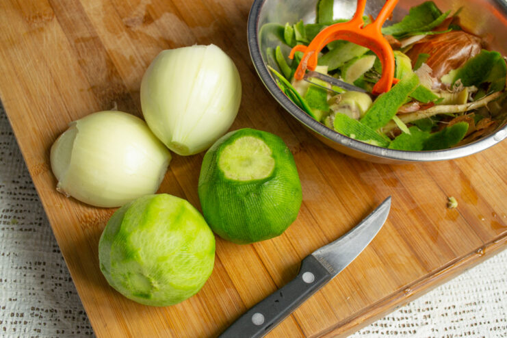 Peeling the green radish for the salad. A hand peeling a green radish with a vegetable peeler.