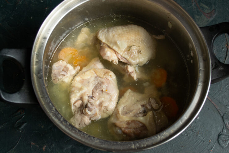 Preparing the Chicken for the Salad Cooked chicken thighs on a plate, with the meat being separated from the bones.
