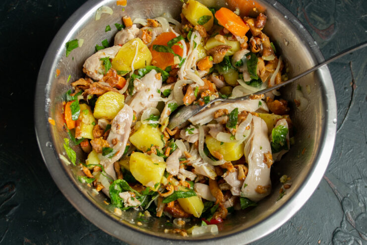 Tossing the Salad to Combine Flavors Mixing the chicken and mushroom salad with the dressing in a large bowl.