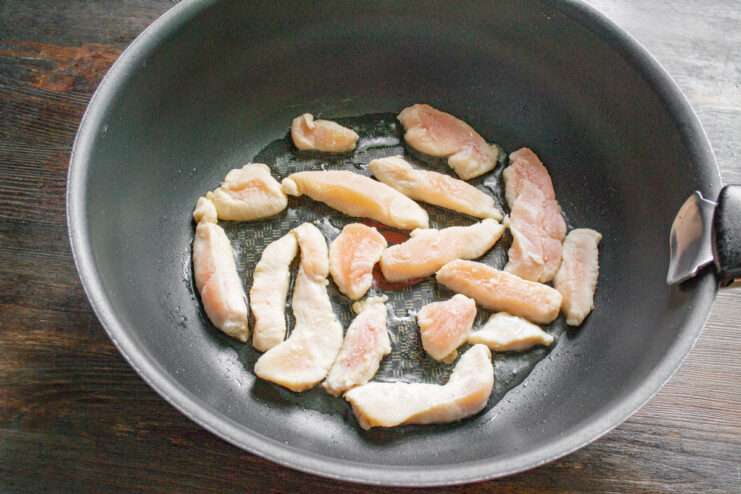 Quickly frying the chicken pieces ensures they are golden brown on the outside and juicy inside. Starch-coated chicken pieces sizzling in a hot wok, turning golden brown.