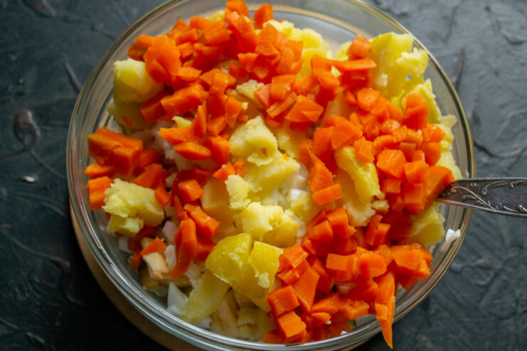 Dicing boiled orange carrots to match the size of the other ingredients. Boiled orange carrots diced into small cubes, ready to be added to the salad.
