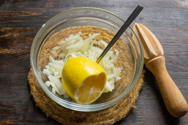 Adding Fresh Lemon Juice to Diced Onions Squeezing fresh lemon juice over finely diced onions in a bowl.