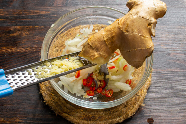 Grating Fresh Ginger for a Zesty Kick Grating fresh ginger root directly into a bowl with other salsa ingredients.