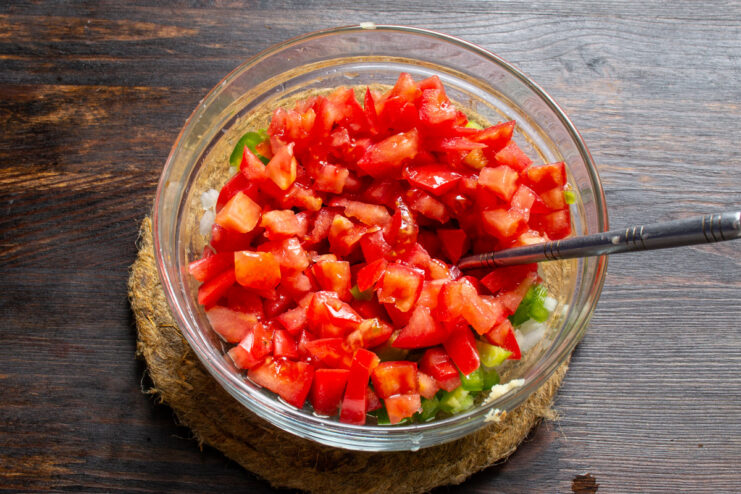 Preparing Fresh Tomatoes for the Salsa Dicing fresh tomatoes into small cubes on a cutting board.
