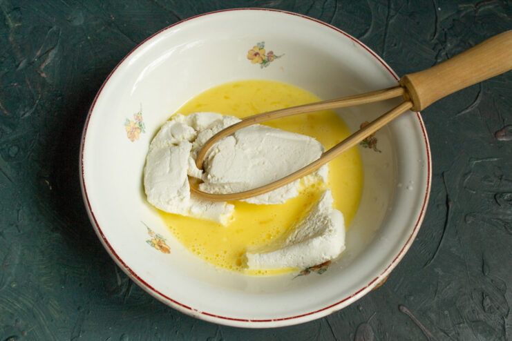 Making the Creamy Tvorog Filling A bowl with tvorog (farmer's cheese) and eggs being mixed together for the pie filling.