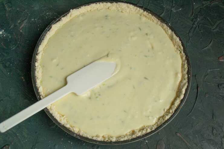 Pouring the Creamy Filling Pouring the smooth cottage cheese filling over the bottom crust layer in the baking pan.