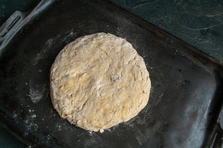 Step 8: Preparing for baking - placing the shaped loaf on a baking sheet. The shaped loaf of soda bread placed on a baking sheet lined with a silicone mat.