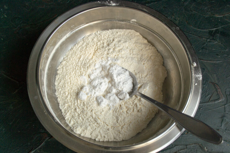 Step 1: Combining dry ingredients - sifting flour and powdered sugar into a bowl. A bowl with sifted flour and powdered sugar being added.