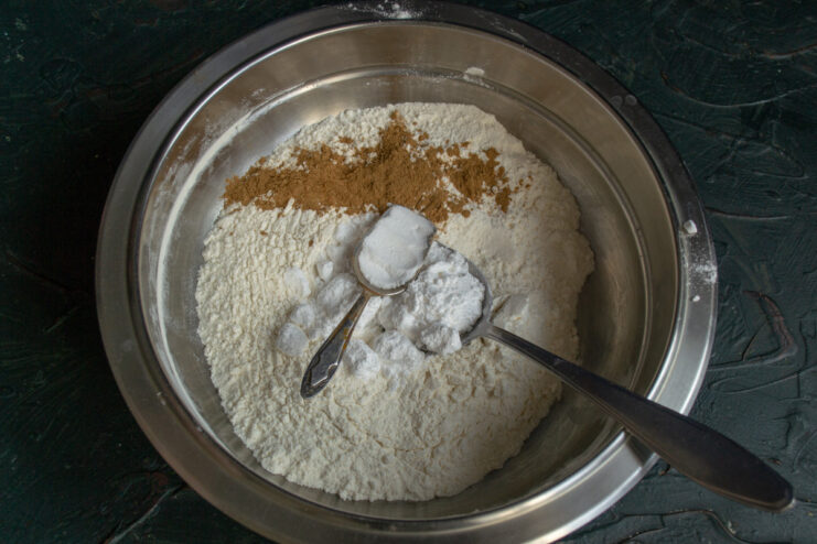 Step 2: Adding leavening agents - baking soda and baking powder. Adding baking soda and baking powder to the flour mixture in a bowl.