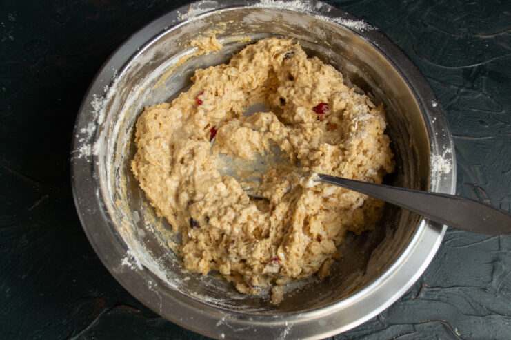 Quickly kneading the sticky dough with a spoon or spatula. A close-up of the sticky, wet dough for the soda bread being mixed.
