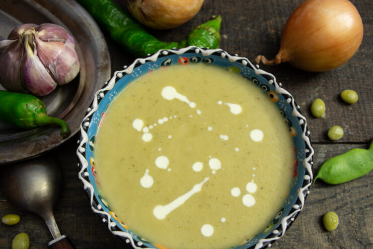 A bowl of finished creamy vegetable soup with chicken broth, garnished with a swirl of cream.