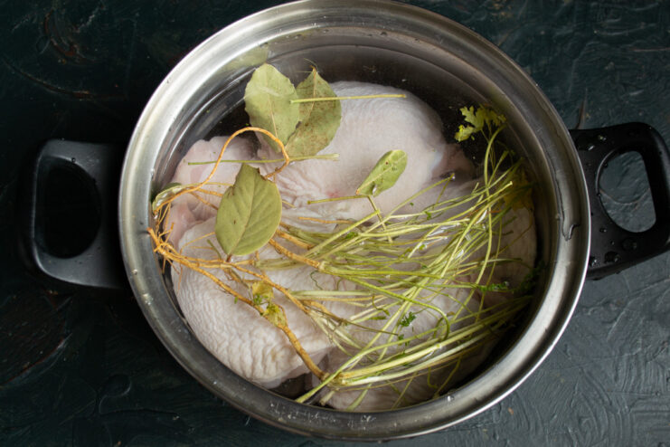 How to Make Clear and Flavorful Homemade Chicken Broth A pot of chicken broth simmering on the stove, with foam being skimmed off the top.