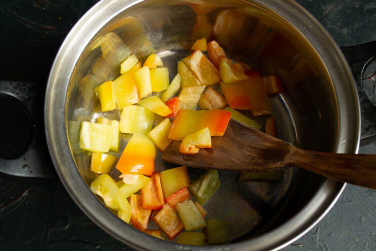 Adding Chopped Bell Peppers to the Soup Pot Coarsely chopped red bell peppers being added to a cooking pot.