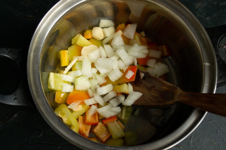 Adding Finely Chopped Onions for Flavor Base Finely chopped onions in a pot with other vegetables for the soup.