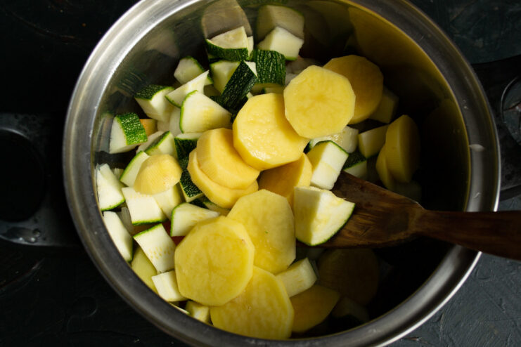 Adding Sliced Potatoes to Thicken the Soup Thickly sliced peeled potatoes in a pot with other soup vegetables.