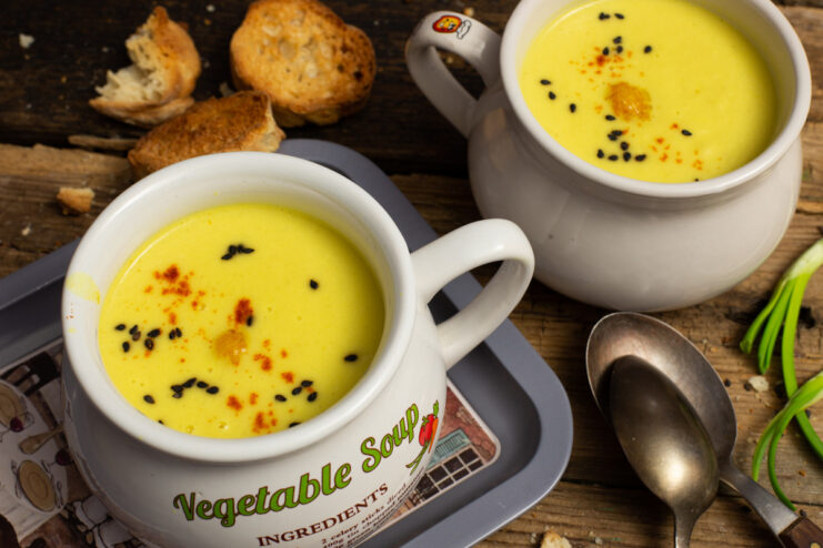 A bowl of creamy cauliflower and celery soup, garnished with black sesame seeds.