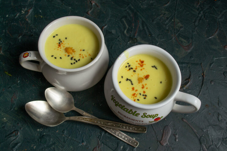 Serving the creamy cauliflower and celery soup. A bowl of creamy cauliflower and celery soup garnished with black sesame seeds and pepper, ready to be served.