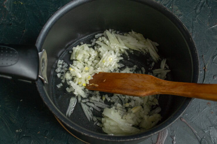 Finely chopping the onion for the soup base. A close-up of finely chopped onions on a cutting board.