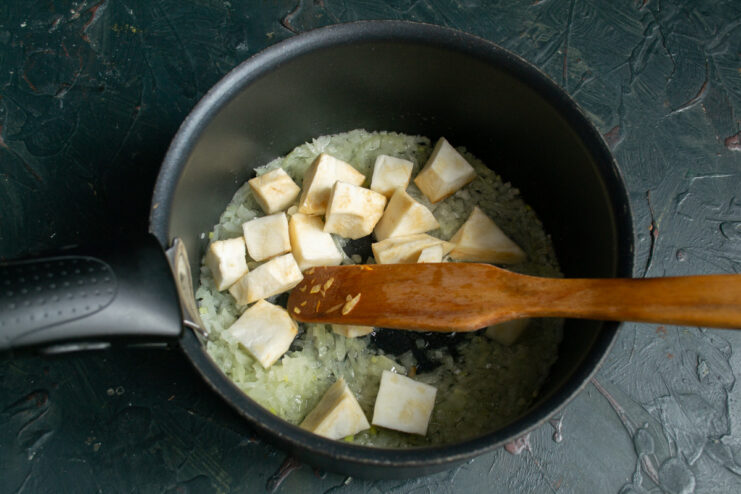 Preparing the celery root by peeling and dicing it. Peeled and cubed celery root on a cutting board, ready for the soup.