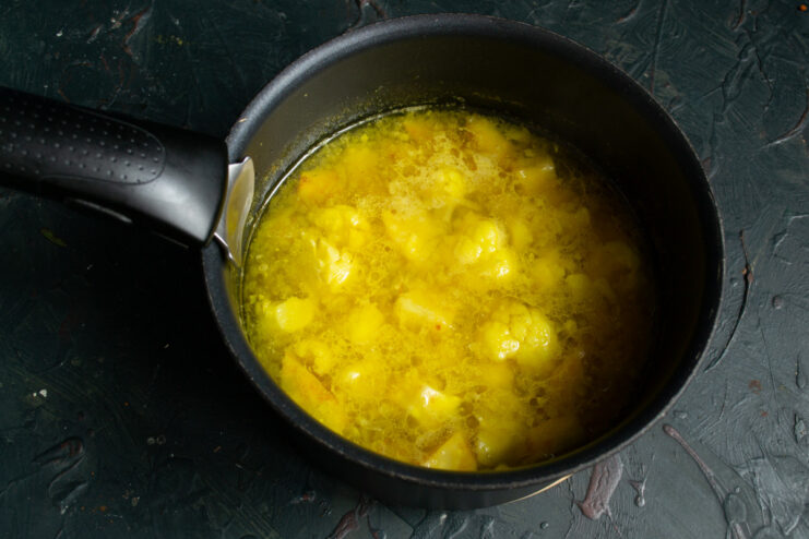 Simmering the soup to soften the vegetables. Vegetable soup simmering in a pot on the stove.