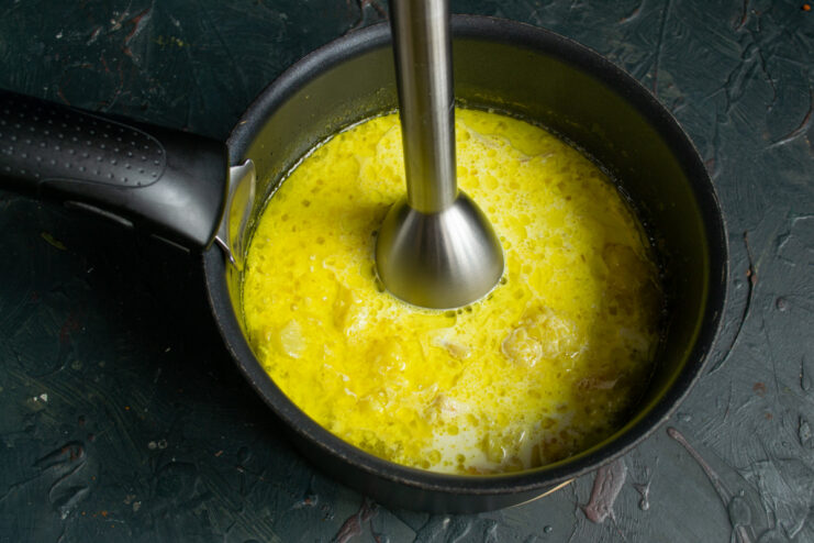 Using an immersion blender to create a smooth soup. Blending the soup with an immersion blender directly in the pot.