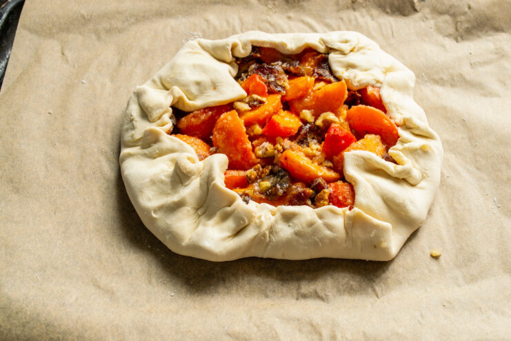 Creating a border by folding the pastry edges over the filling. Folding the edges of the puff pastry over the fruit filling to form a crust.