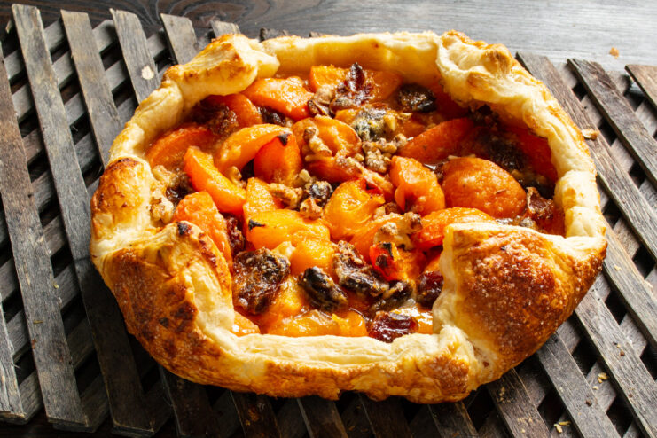 Cooling the freshly baked pie before serving. The finished golden-brown puff pastry pie with apricots and dates cooling on a wire rack.
