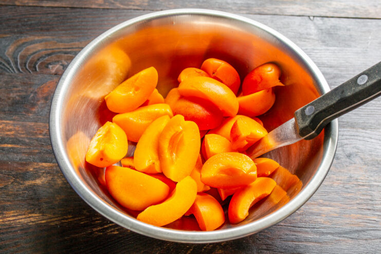 Slicing fresh apricots for the pie filling. A pile of freshly sliced apricots in a bowl for the pie filling.