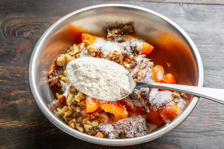 Adding flour to the filling to thicken the fruit juices. Sprinkling a spoonful of all-purpose flour into the fruit filling mixture.