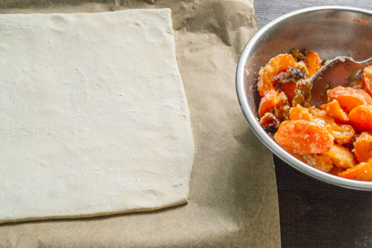 Rolling out the puff pastry to the perfect thickness for the pie base. A sheet of puff pastry being rolled out on a floured surface.