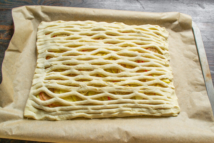 Carefully placing the puff pastry lattice top over the apple filling.