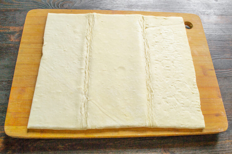 A sheet of thawed, ready-made puff pastry on a floured surface.