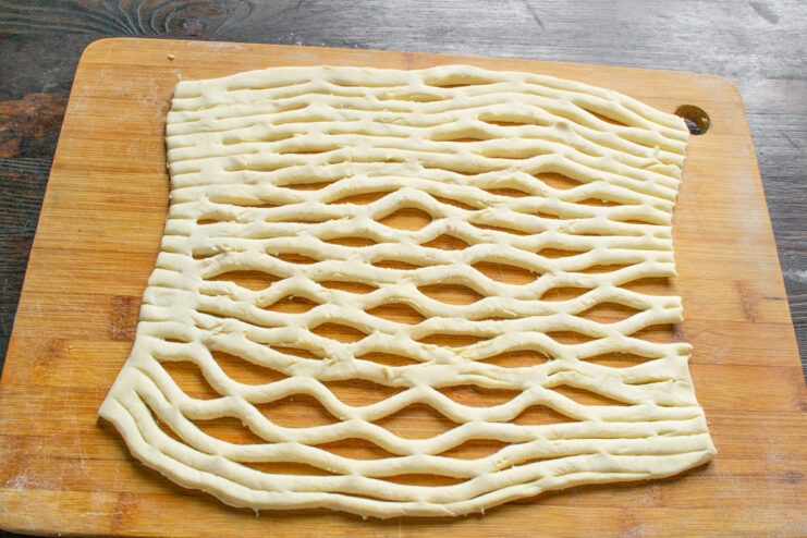 Using a lattice roller to create a net pattern on a sheet of puff pastry.