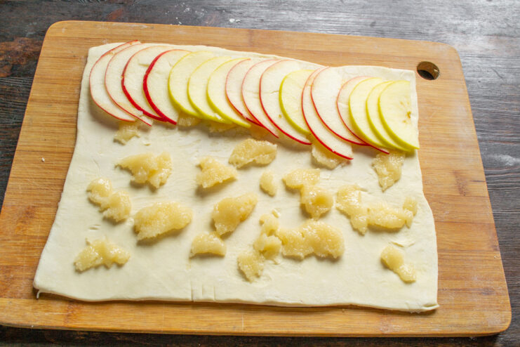 Layering thin apple slices over the honey-covered puff pastry base.