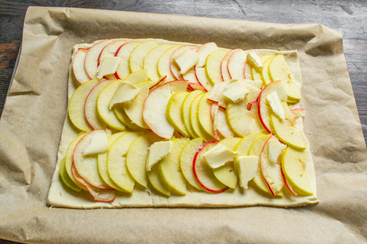Placing small cubes of butter over the layer of sliced apples.