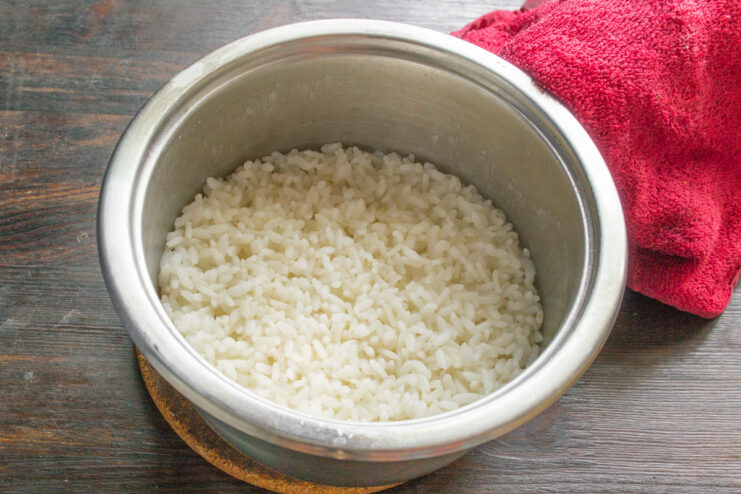 Cooking Sushi Rice for the Salad Base A pot of rice cooking on a stove for the layered salad base.