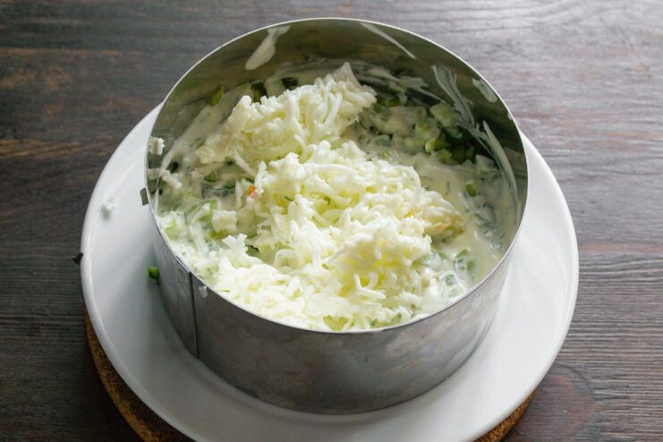 Creating the Grated Egg White Layer Adding a layer of finely grated egg white over the cucumber layer and spreading it with dressing.