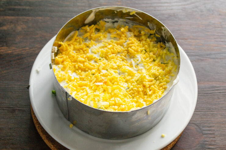 Adding a Bright Layer of Grated Egg Yolk Sprinkling finely grated egg yolk over the egg white layer in the cooking ring.