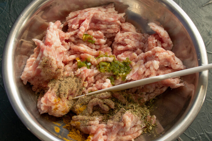 Seasoning the ground meat for the cutlets. A bowl of ground meat with paprika and other seasonings being added.
