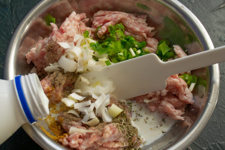 Adding milk to the ground meat to make the cutlets juicier. Cold milk being poured into the bowl with the ground meat mixture.