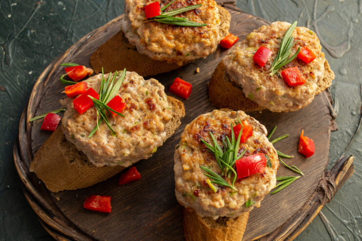 Serving the freshly cooked cutlets on rye bread. Cooked cutlets served on rye bread slices, garnished with red bell pepper and rosemary.